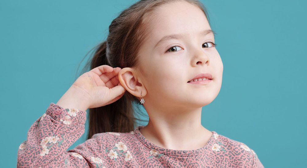 Cute little girl showing new earrings on ear